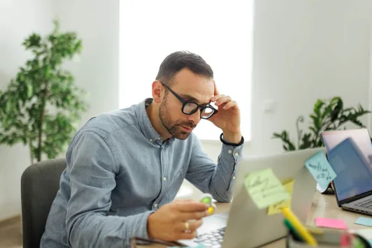 Homem de óculos no escritório, distraído entre post-its coloridos